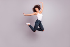 Full length full size fullbody portrait of playful, crazy, childish, funny, pretty, charming positive girl jumpink with hands up, looking at camera, isolated on grey background, having fun