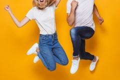 Young loving couple jumping isolated over yellow wall background.
