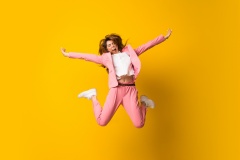 Young woman jumping over isolated yellow wall making victory gesture