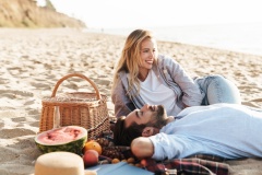 Lovely young couple having a picnic at the beach