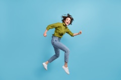 Photo portrait of woman running jumping up laughing isolated on pastel light blue colored background