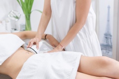 Young woman having radiofrequency lifting stomach treatment at beauty spa salon.
