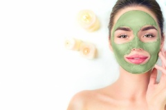 Spa. Young woman applying facial green clay mask in spa salon. Beauty treatments. Skincare. Top view