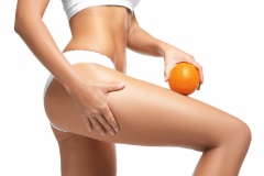 Young woman holding orange on white background. Cellulite problem concept
