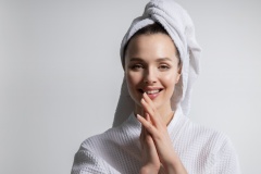 Young woman wearing bathrobe and wrapped towel on head show beautiful smile and perfect skin.