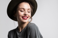 Close up of cool young girl student in stylish black hat and casual clothes cute smiling with a good mood and positive thoughts demonstrating white teeth isolated on gray background. Perfect smile.