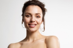 Close up of young joyful woman with naked shoulders posing after cosmetic skin rejuvenation procedure. Advertising poster of natural skincare cosmetic products.