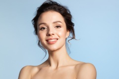 Smiling young woman with natural perfect skin beauty studio portrait.